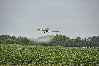 Airplane pesticide spray on field crops