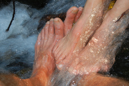 Two pairs of feet underneath a waterfall