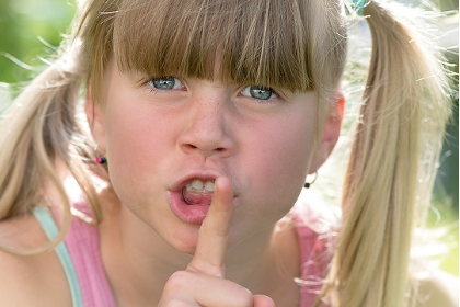 blonde girl holding her finger over her lips