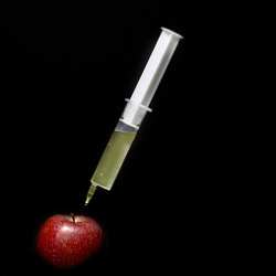 A syringe stuck inside a red apple