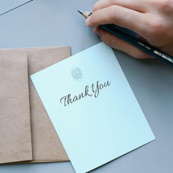 Person writing in a thank you card