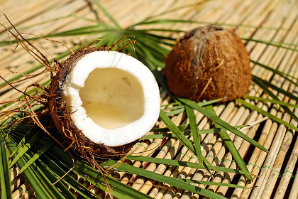 Split open coconut laying on a mat with palm leaves