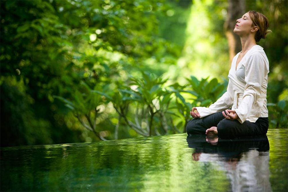 Woman sitting next to a river meditating