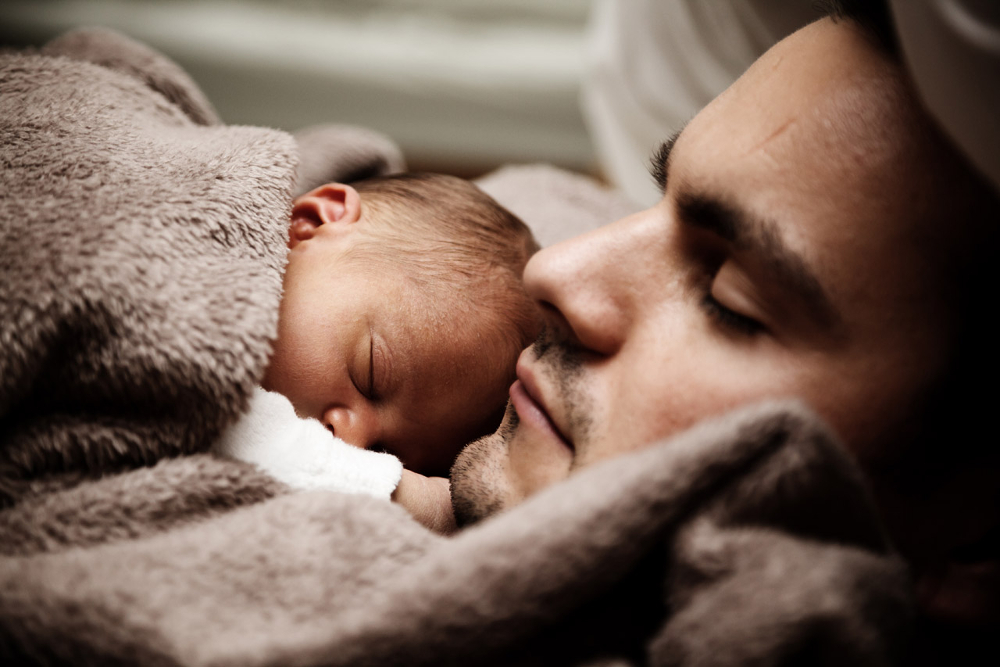 Father and newborn sleeping peacefully