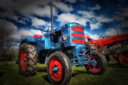 Blue tractor set against ominous clouds on a farm field