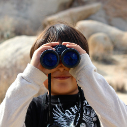 Boy holding a pair of binoculars up to his eyes
