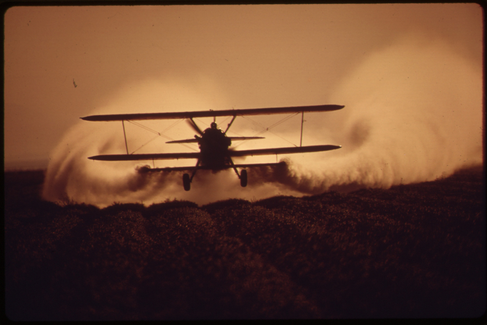 Plane spraying crops with pesticides, also known as crop dusting
