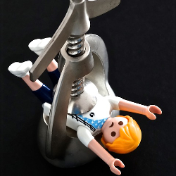 Toy person in a vice grip being squeezed