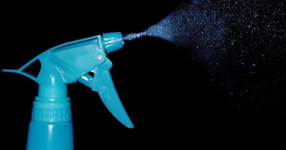 Blue spray bottle spraying a clear liquid