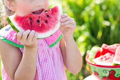 Girl eating a watermelon during a sunny summer day