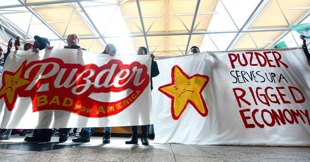 Fast food workers at a Fight for $15 protest against CEO Pudzer