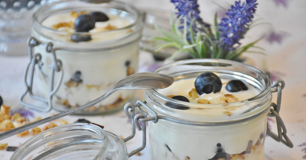 Yogurt and blueberries in glass jars with lavender flowers