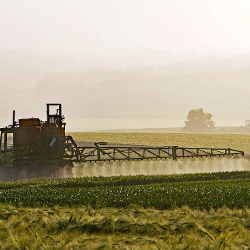 Industrial machine spraying herbicide over a farm crop field