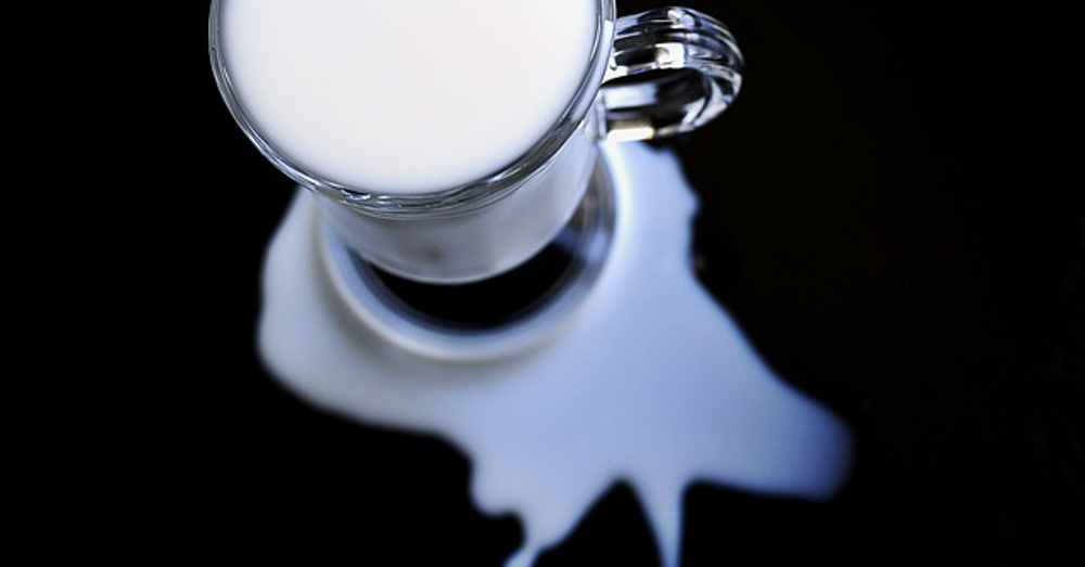 Glass of milk with a small spill on the counter