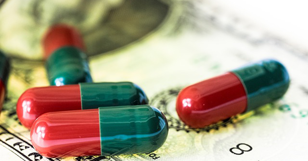 Pharmaceutical pills and capsules spread out on a dollar bill