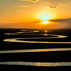 Winding and meandering river in the light of a sunrise on the prairie