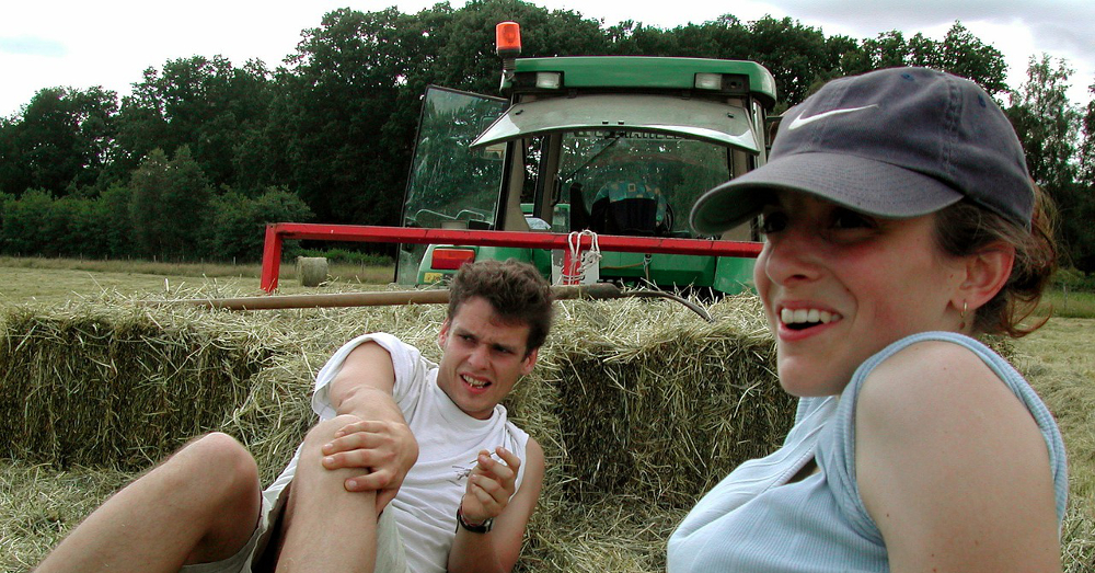 Young farmers sitting in a hay field near a tractor