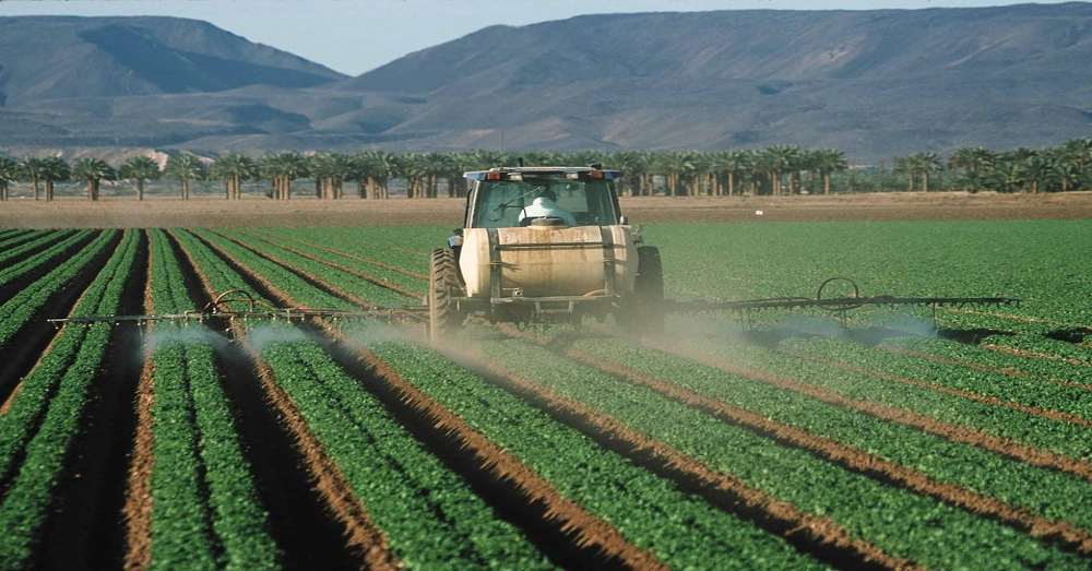 Farmer on tractor spraying fields with pesticides