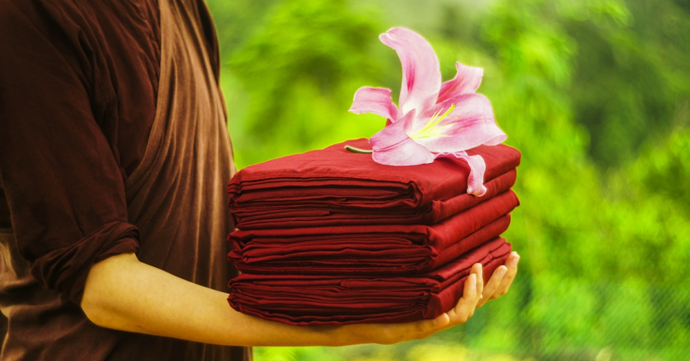 Someone holding a stack of folded linens with a flower on top
