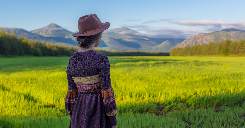 woman looking over a countryside farm field with mountains