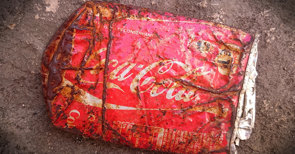 crushed coca cola can littered on the ground