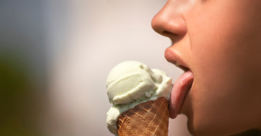 A woman licking a vanilla ice cream cone
