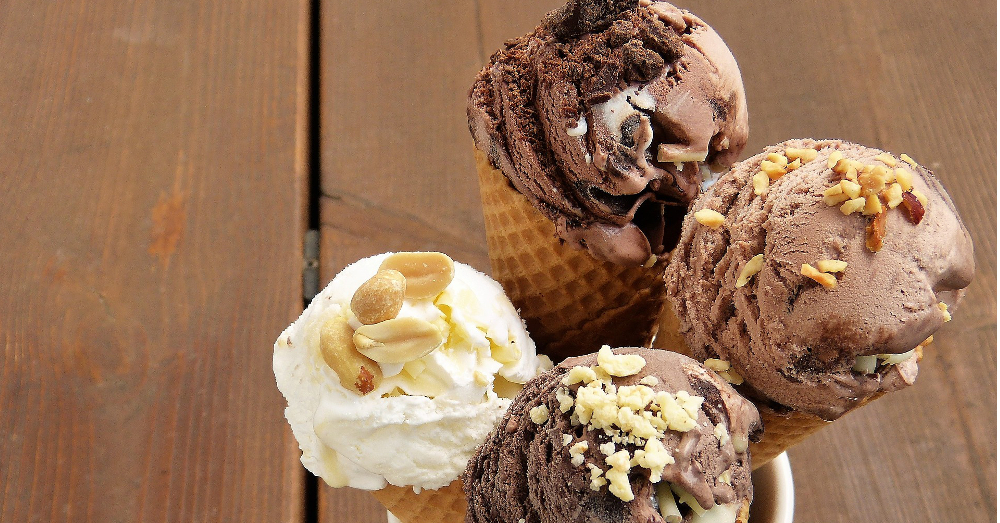 four different flavors of ice cream in waffle cones