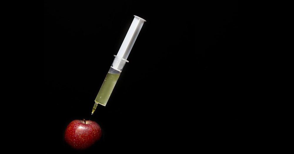 syringe of mystery substance injected into an apple