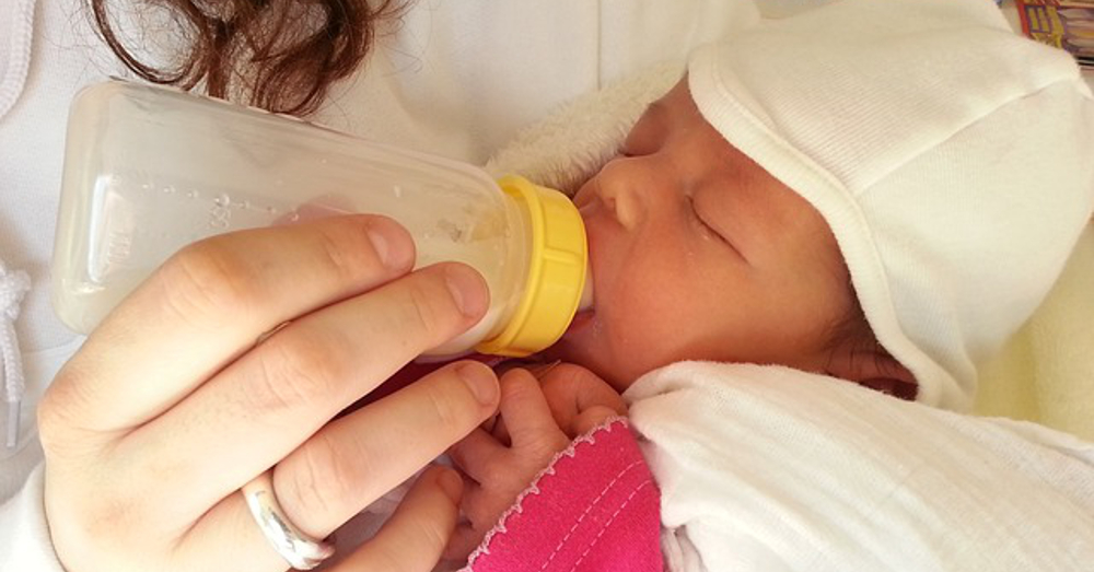 mother feeding newborn infant with a bottle