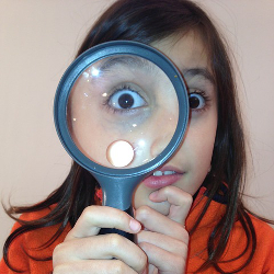 girl holding a magnifying glass to her eye