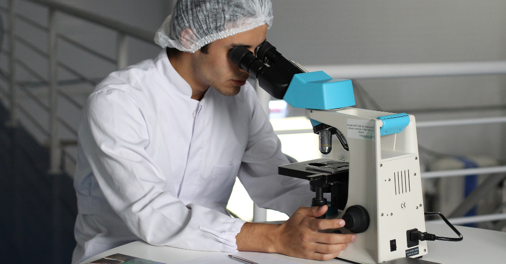 scientist in a lab coat using a microscope