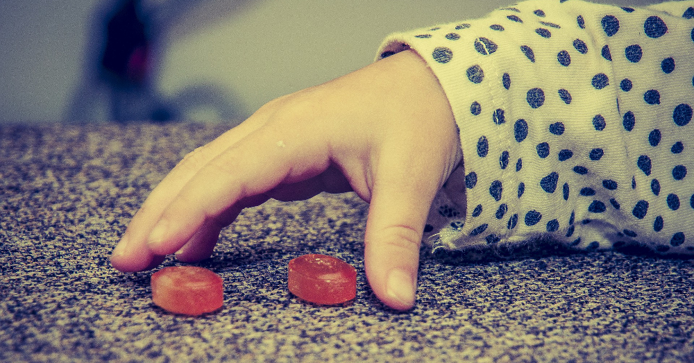 hand of a child reaching out to grab red candies
