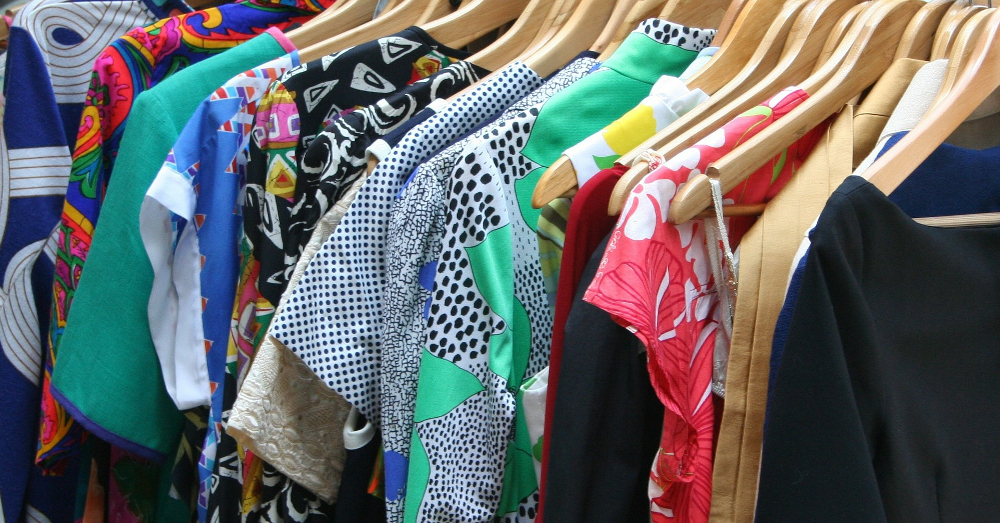 closet full of shirts dresses and other clothing on wooden hangers