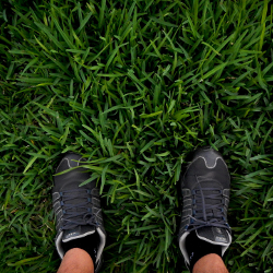 feet in sneakers standing on lush green grass