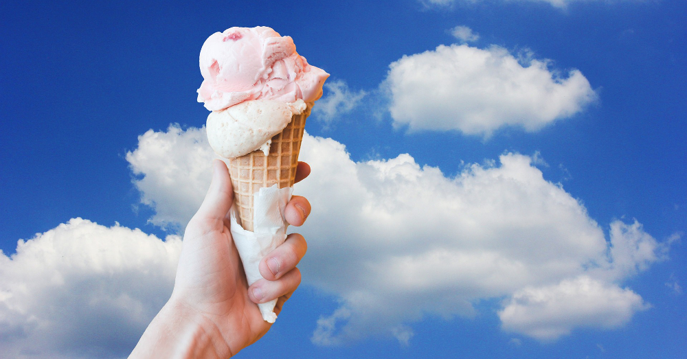 scoop of ice cream in a waffle cone against a partly sunny sky