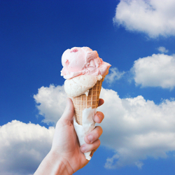ice cream in a waffle cone against blue sky with clouds