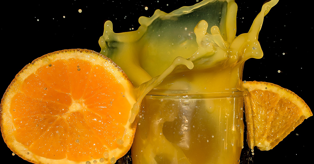 splashing orange juice in a glass with orange slices and wedges