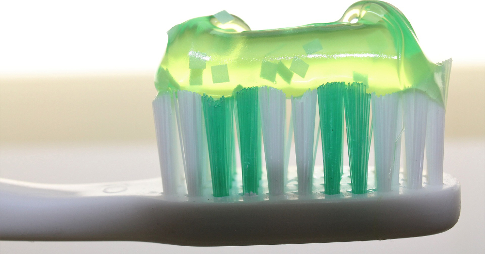 green plastic toothbrush with green toothpaste