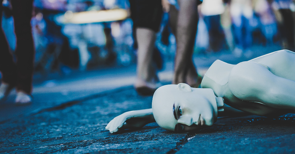 mannequin lying broken on the ground while people walk by