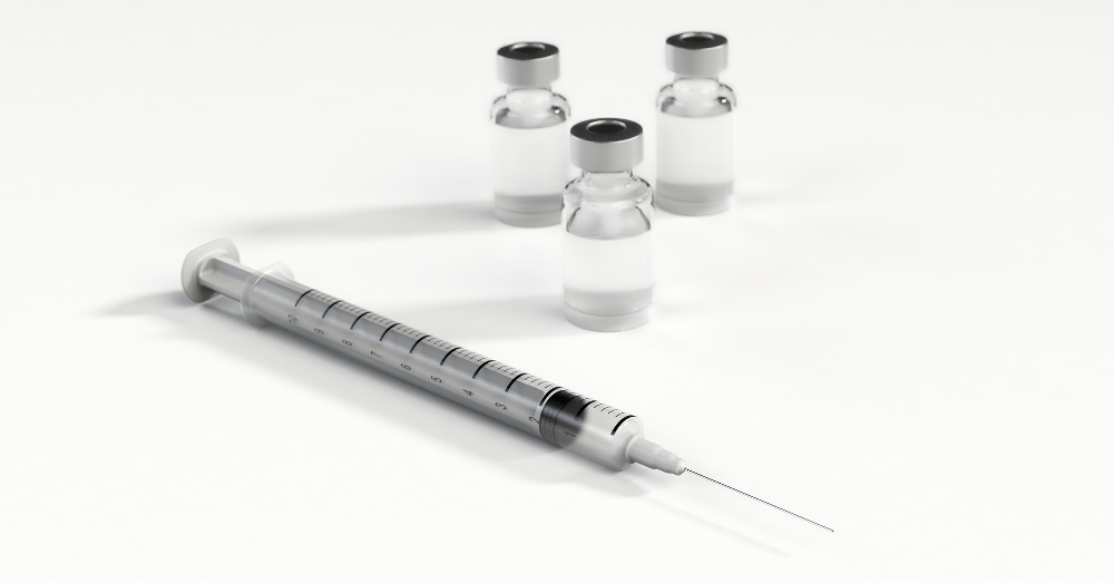 empty syringe with three glass bottles of vaccinations