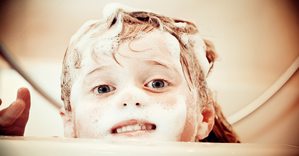 child washing their hair in a bathtub