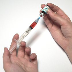 hands holding a syringe filled with red liquid