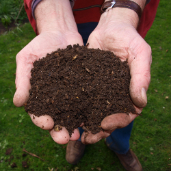 man on a farm holding a handful of composted soil