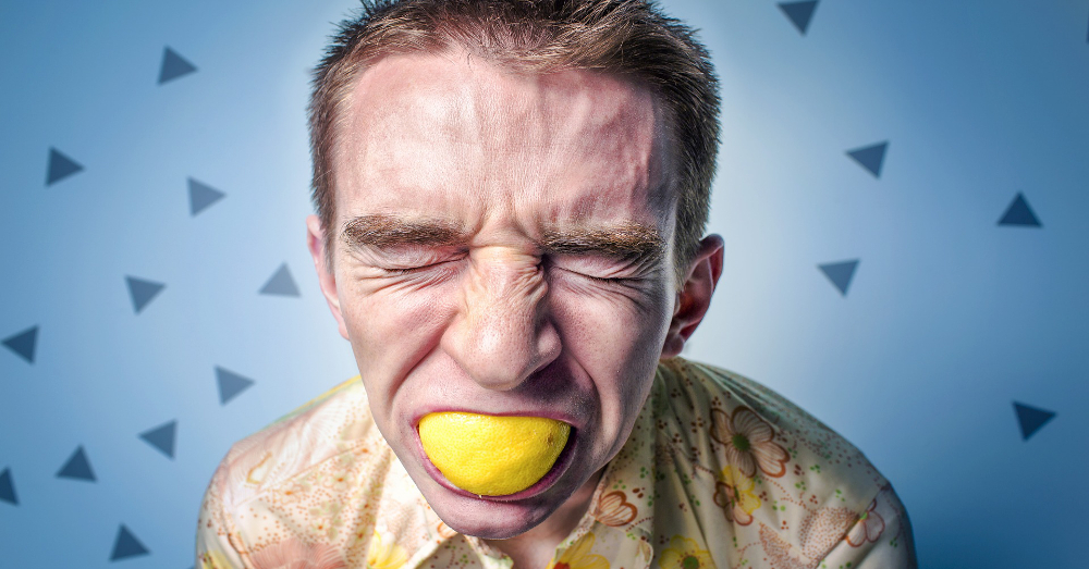 man eating a sour lemon and wincing