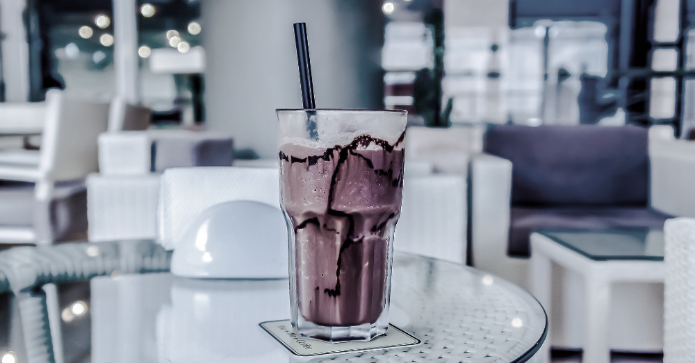 black and white image of a milkshake at a cafe in a glass container with a straw