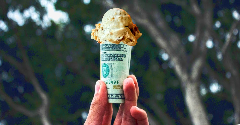 hand holding an ice cream cone made of twenty dollar bills