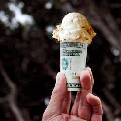 hand holding an ice cream cone made of twenty dollar bills