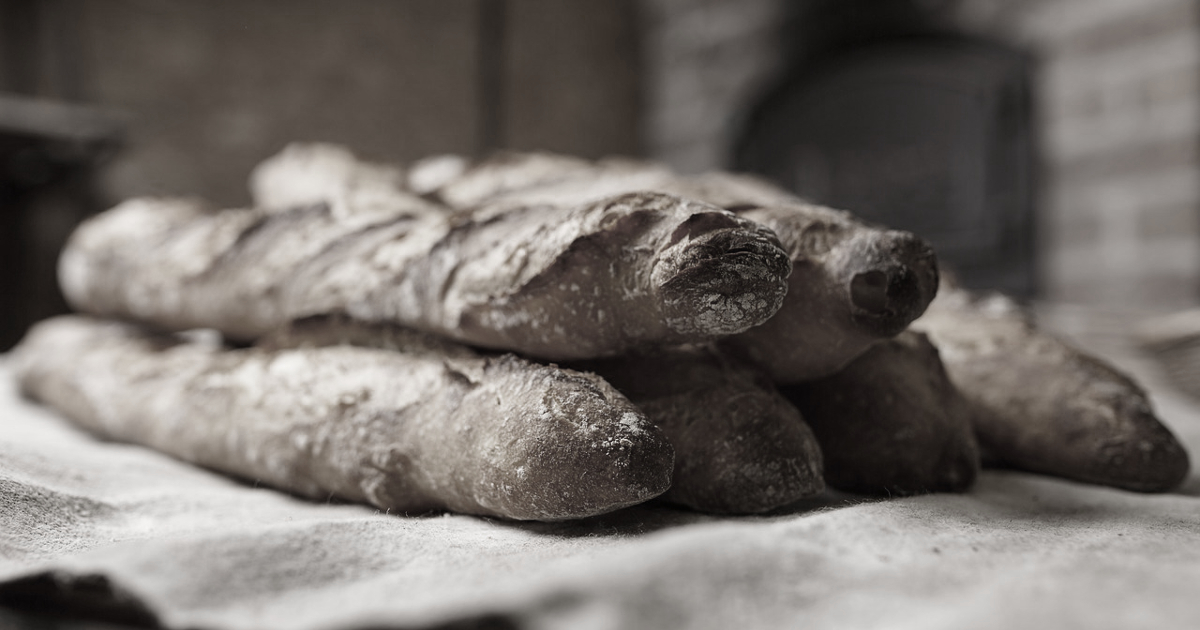 black and white image of a stack of French style baguettes in a brick bakery