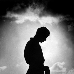 silhouette of a man bowing his head in remembrance