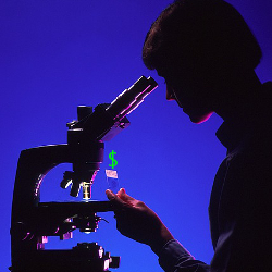 silhouette of a scientist in front of a microscope with a dollar sign on their slide